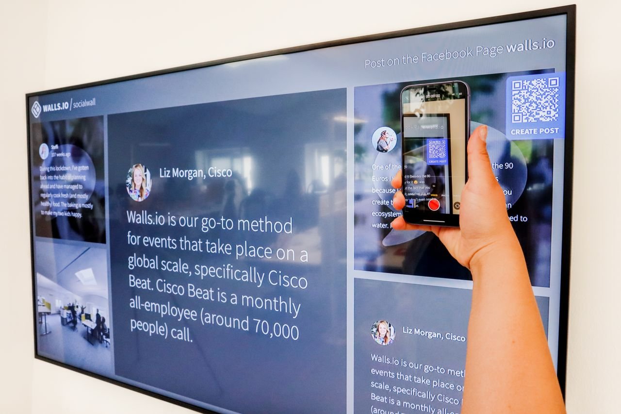 about-us-01 Hand holding smartphone scanning QR code on a large digital display. Technology and connectivity concept.